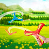 A hand holds a red soft foam boomerang flying disc against a bright green outdoor landscape.