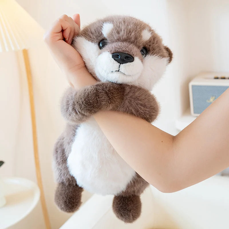 A person is holding a gray and white magnetic otter plush toy close to their face.