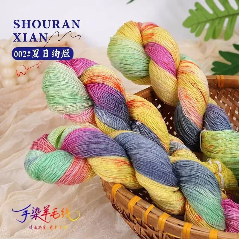 A bundle of hand-dyed Australian wool yarn in a vibrant gradient of pink, yellow, green, and purple, displayed in a woven bas