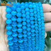 A hand holds a strand of bright blue cat eye stone beads for jewelry making