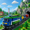 A model train locomotive in blue and green sits on a track surrounded by green landscape and trees.