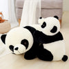 A white and black panda plush pillow sitting on a light wooden surface.