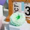 A light green squishy stress relief ball with a visible green center is displayed on a white block.