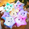 A collection of glowing star-shaped plush pillows with LED lights arranged on a brown surface.