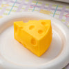 A yellow cheese-shaped squishy toy resting on a white plate.
