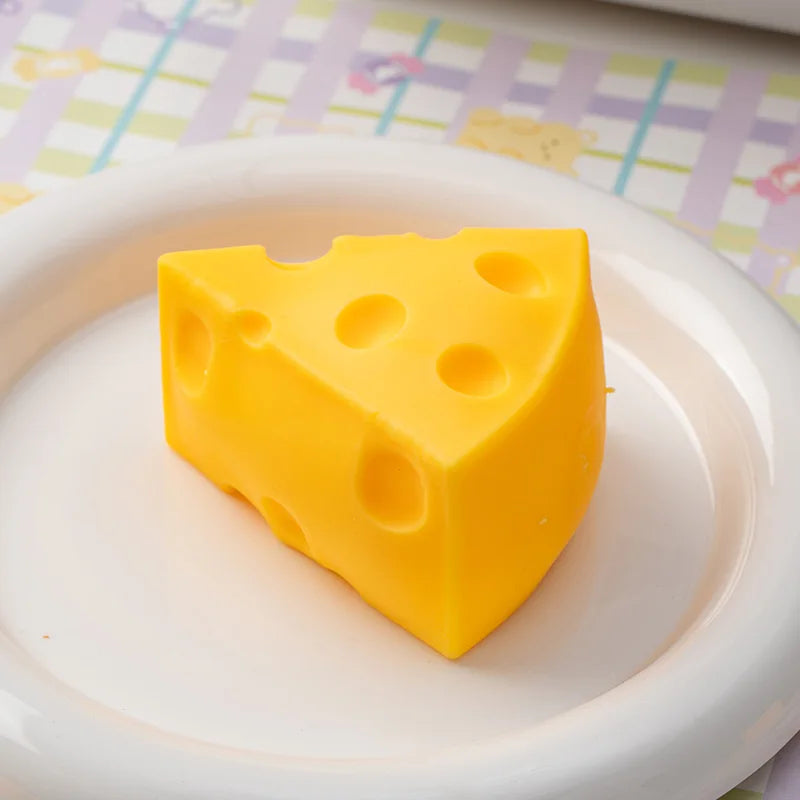 A yellow cheese-shaped squishy toy resting on a white plate.