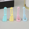Four colored ergonomic yarn guide rings in light blue, yellow, pink, and light blue are displayed on a gray surface.