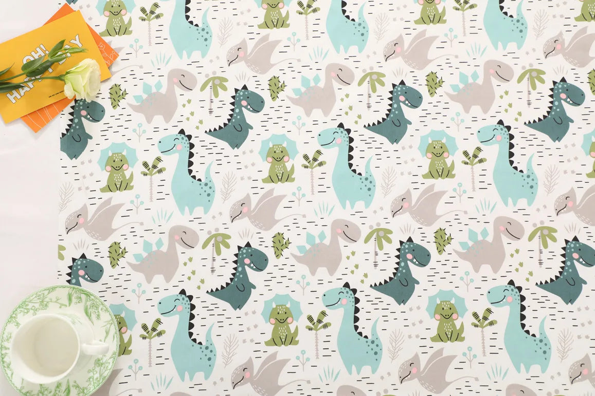 A fabric print featuring a grid pattern of various dinosaur silhouettes in shades of green, teal, and gray.