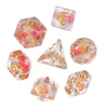 A set of translucent, mushroom-shaped polyhedral dice in pink and yellow tones.