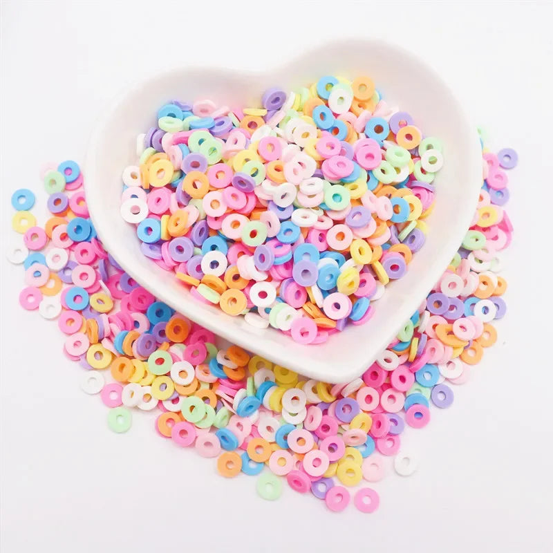 A white heart-shaped dish filled with colorful polymer clay sprinkles for slime and craft decor.