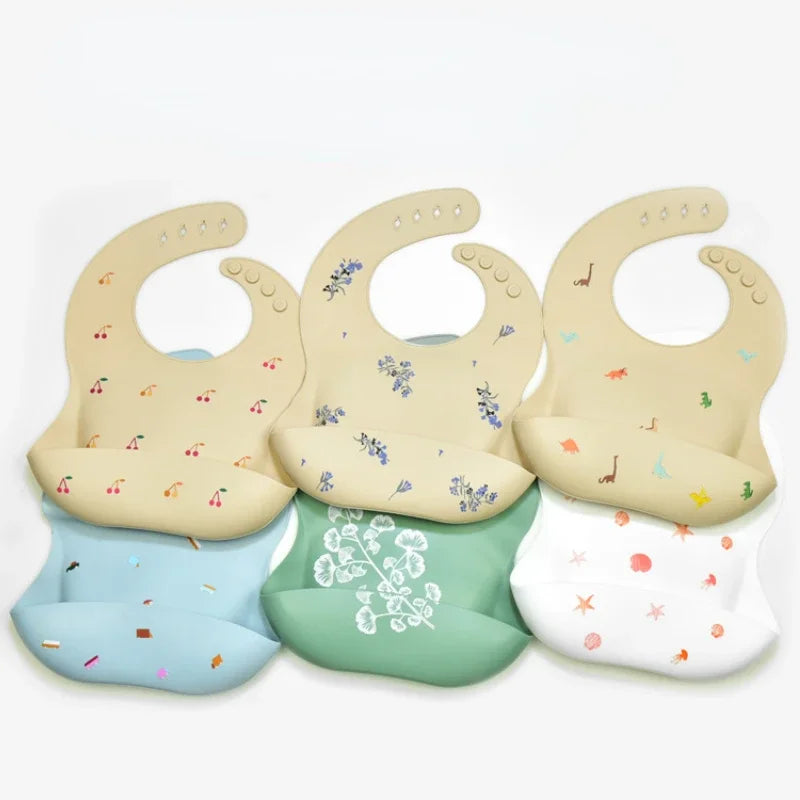 A set of soft silicone waterproof baby bibs in various pastel colors with adjustable necks.