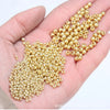 A hand holds a cluster of small, gold-colored metallic glass beads for jewelry and crafting.