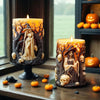 A candle in a dark pot features an orange Halloween witch portrait molded into the wax.
