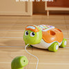 A green turtle toy is shown with a phone line, demonstrating how a baby can pull the line to move the car forward.