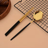 A set of six stainless steel Korean dinnerware and chopsticks resting on a black grid mat.