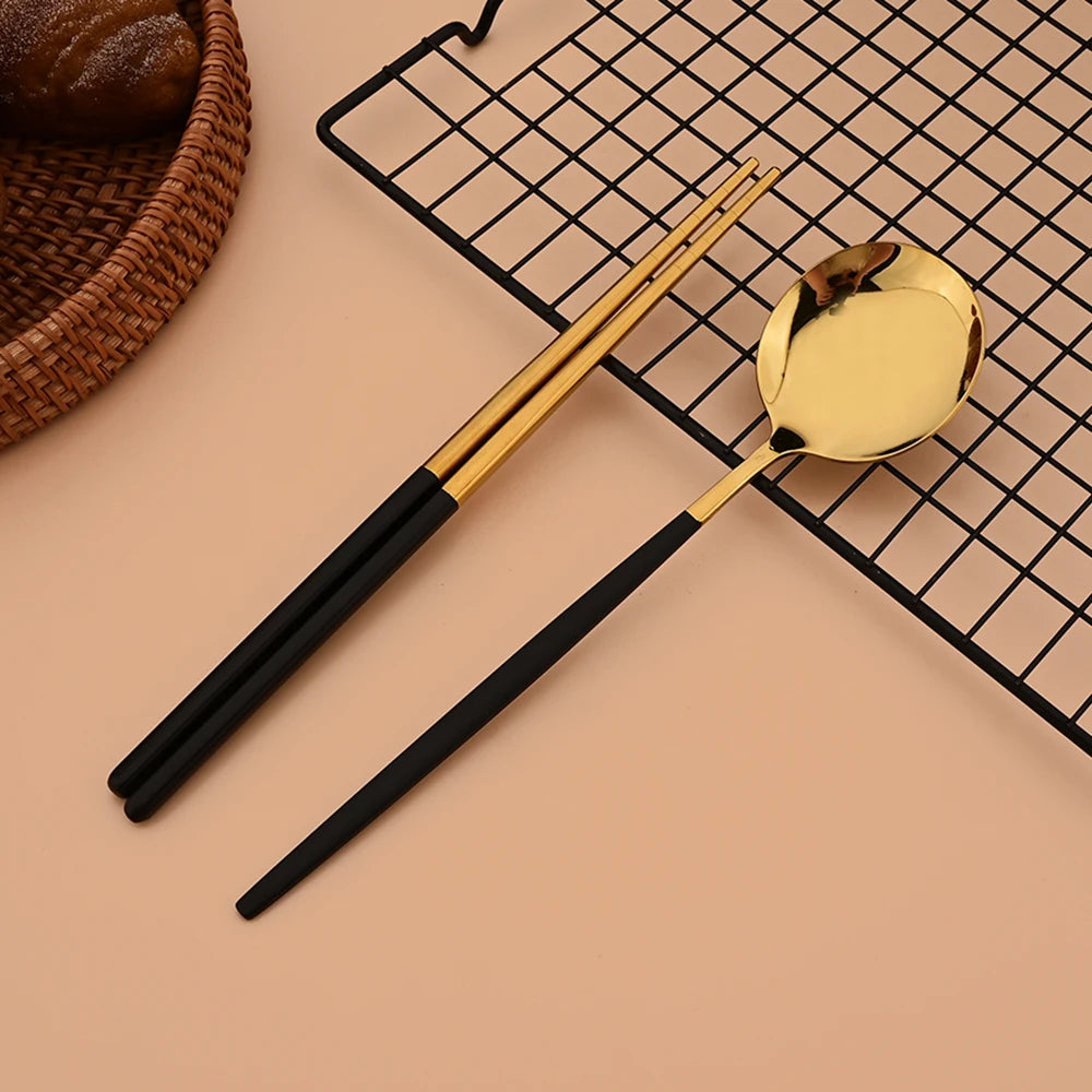 A set of six stainless steel Korean dinnerware and chopsticks resting on a black grid mat.