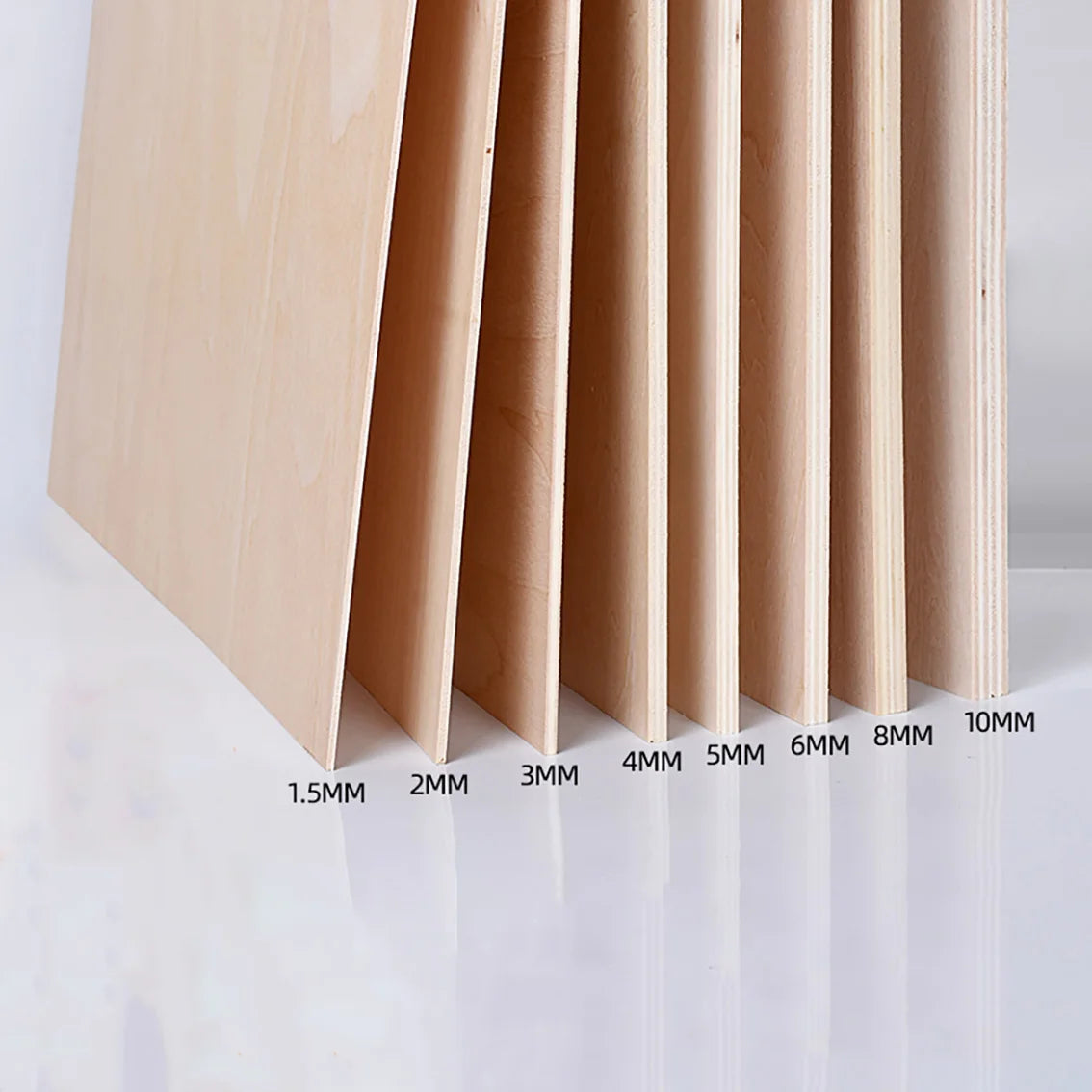 A close-up view of light wood craft sheets cut into vertical slats, showing varying thicknesses from 1.5mm to 10mm.