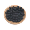 A pile of small, black silicone round beads in a wooden bowl for jewelry making and crafts.