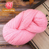 Pink yarn skein shown on a wooden surface, ready for knitting or weaving projects.