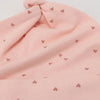 A pink knitted baby hat with a gathered top and small heart embroidery.