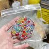 A hand holds a clear plastic bag filled with colorful squishy beads for stress relief.
