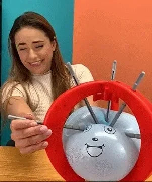 A woman is holding a red ring with several metal spikes, which is part of the Balloon Pop Party Game.