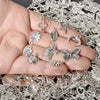 A hand holds a collection of silver mixed metal charms for DIY jewelry making