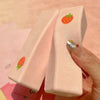 A hand holds a pink strawberry milk squishy stress relief toy with a glittery fingernail.