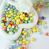 A heart-shaped ceramic bead display featuring a colorful mix of yellow, green, and reddish-orange beads.