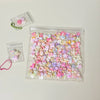 A clear plastic bag filled with numerous pink and purple kawaii cat paw squishy stress relief fidget toys.