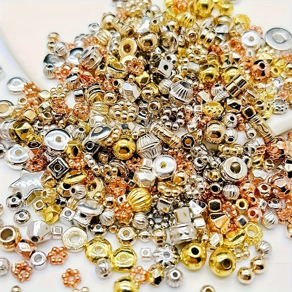 A pile of mixed color acrylic spacer beads in gold, silver, and rose gold tones for jewelry making
