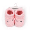 Pair of pink knitted baby booties with a cute face design