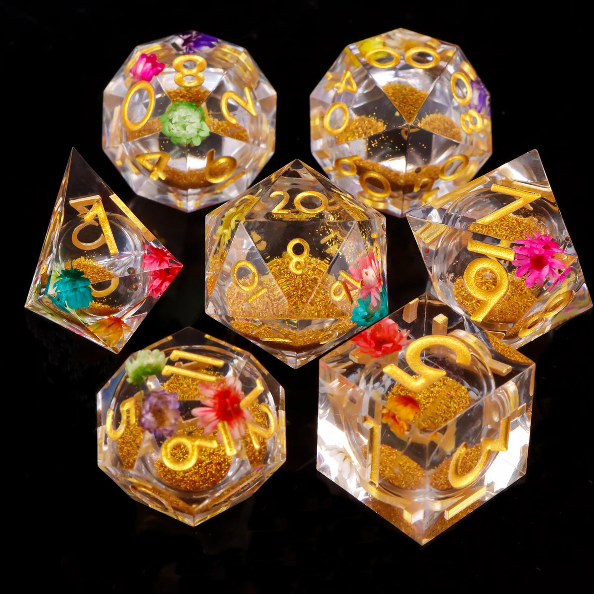 A collection of polyhedral dice in clear and amber plastic, featuring gold glitter and colored accents.