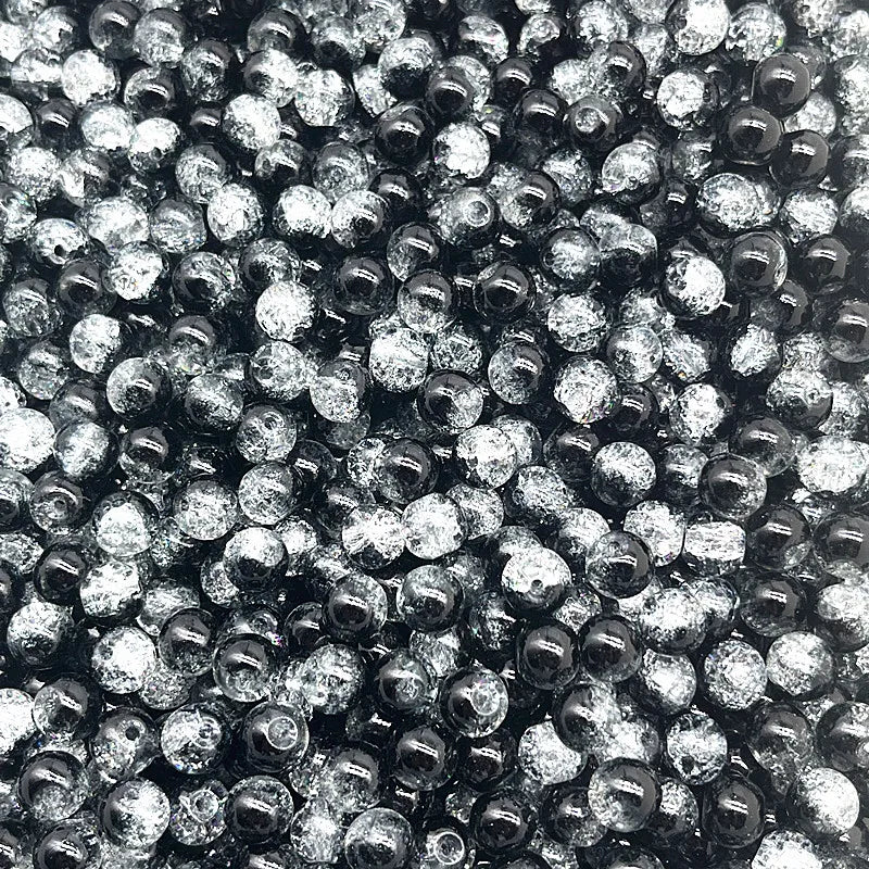 A close-up view of small, round glass crackle beads in various shades of black and clear.