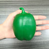 A hand holds a bright green squishy bell pepper fidget toy for stress relief.