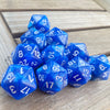 A pile of ten bright blue pearl acrylic D20 dice resting on a wooden surface.