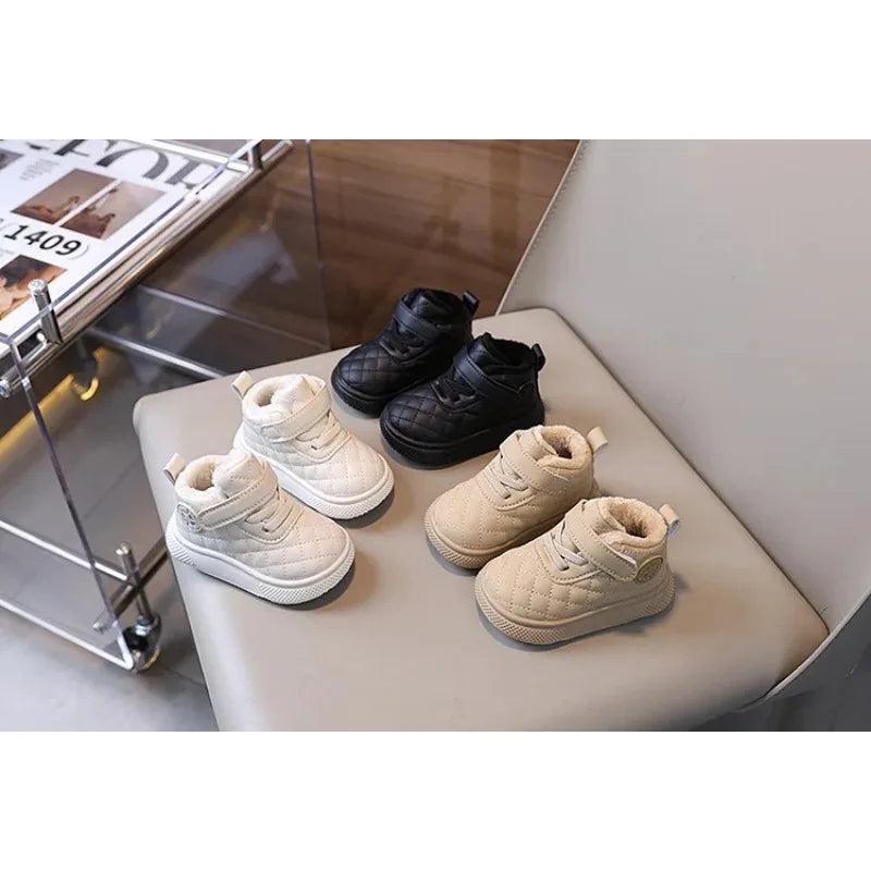 A display of black and beige toddler winter snow boots with soft soles and Velcro closures.