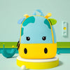 A yellow and blue 3D animal kids backpack shaped like a hippopotamus sitting on a light green surface.