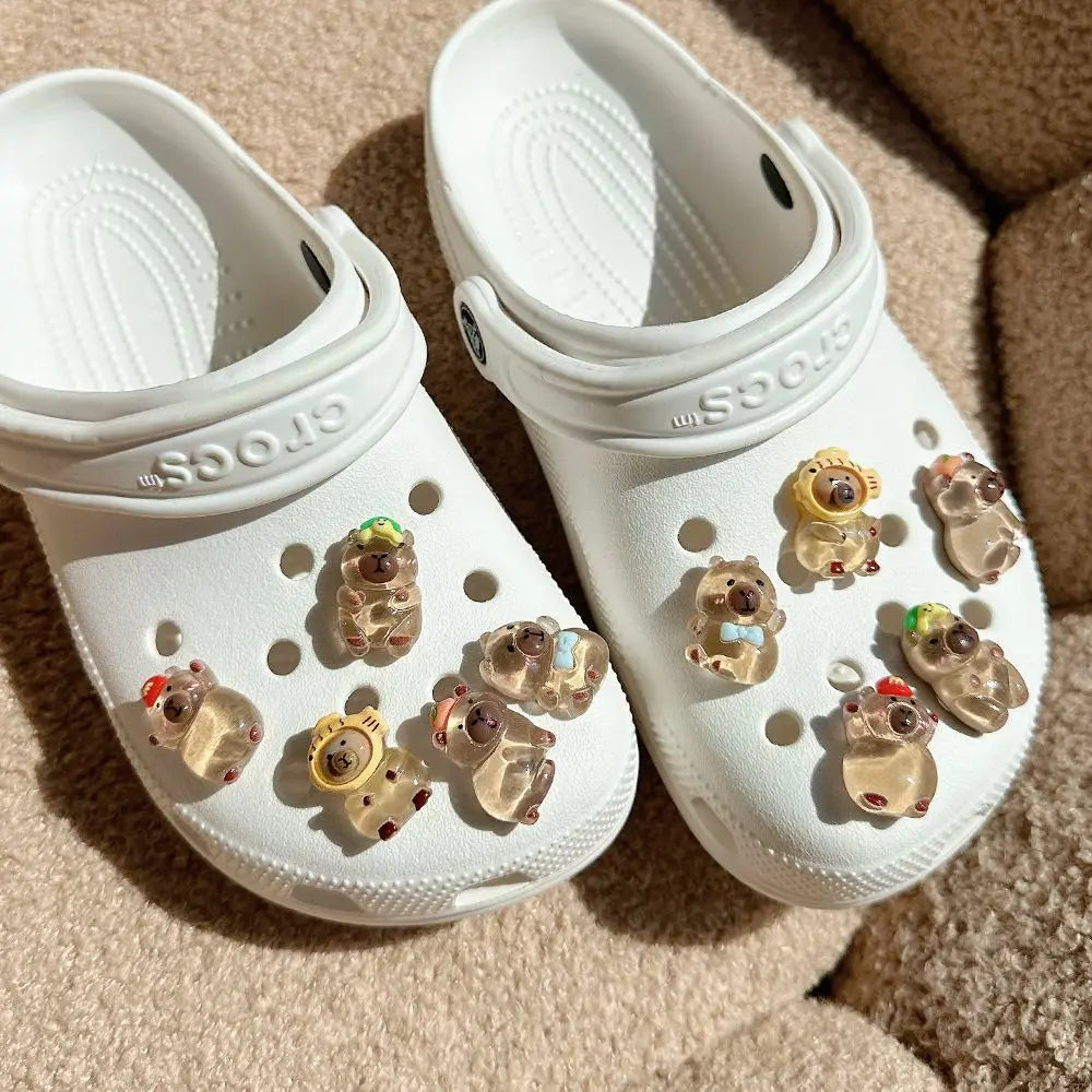 A pair of white Crocs shoes with glow-in-the-dark capybara charms inside the foot cups.