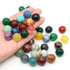 A hand holds a collection of natural amethyst and rose quartz crystal spheres in various colors.