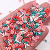 A hand holds a pile of red and white polymer clay slices for DIY crafts.