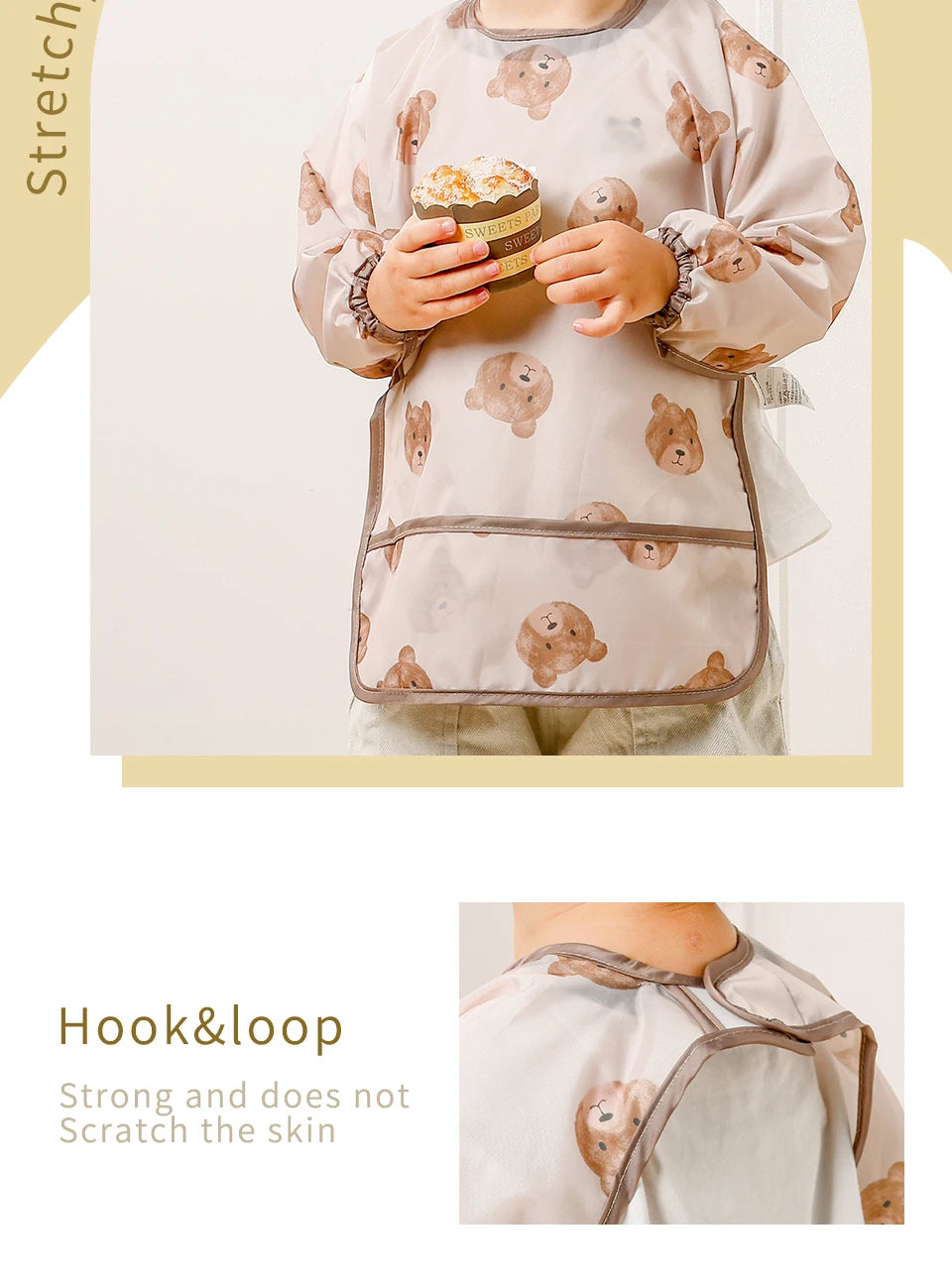 A baby wearing a light beige waterproof long sleeve feeding bib decorated with small bear patterns.