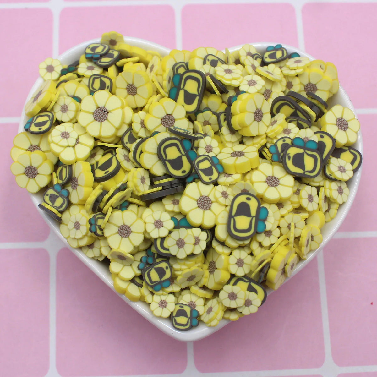 A pile of assorted polymer clay sunflower and bee slices for crafts in yellow and blue colors.