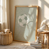A framed canvas wall art featuring a soccer ball silhouette and tree shadows on a light background.