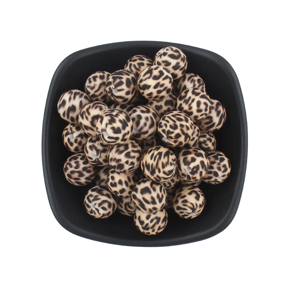 A black bowl filled with small, round, leopard-print silicone beads for jewelry making.