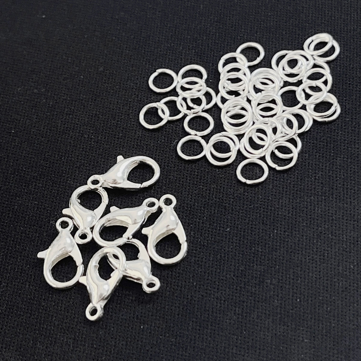 A collection of gold and silver lobster clasps and open jump rings for jewelry making.