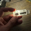 A hand holds a clear, hand-cranked fidget light bulb with an LED inside.