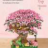 A detailed LEGO set of a pink cherry blossom tree in a house landscape with small flowers and lighting.