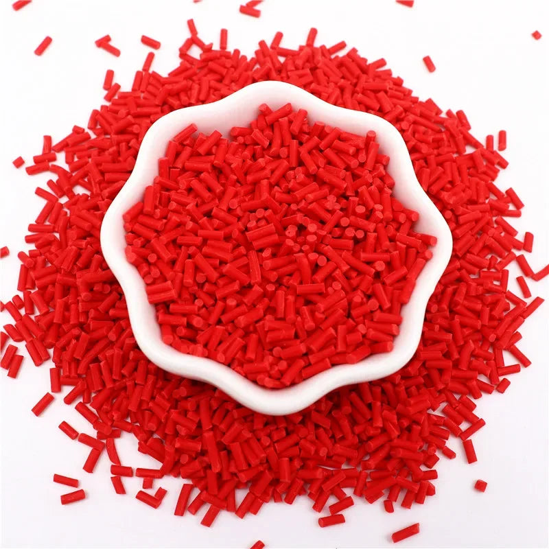A pile of bright red polymer clay slice sprinkles scattered on a white background.