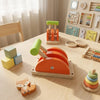 A wooden Montessori busy board for toddlers featuring gears, switches, and an orange sensory activity board.